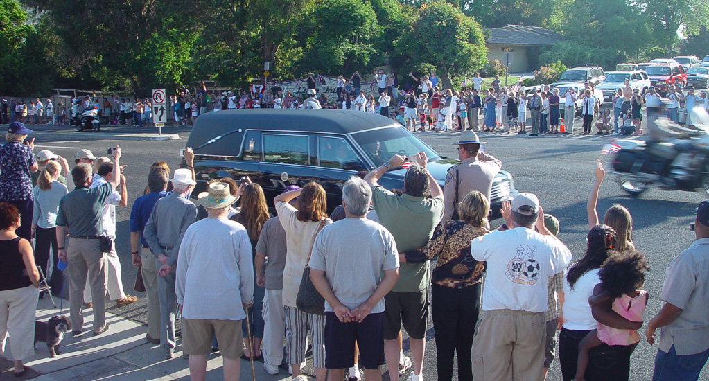 Well wishers watch as the motorcade carrying President Ronald Reagan passes by them in Thousand Oaks, California en route to the Ronald Reagan Presidential Library